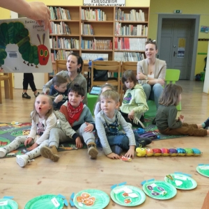 Prowadząca zajęcia przedstawia dzieciom książkę "Bardzo głodna gąsienica"