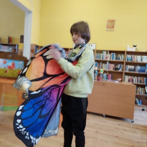 Chłopiec z pomocą opiekuna przymierza skrzydła motyla