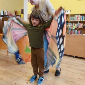 Chłopiec z pomocą opiekuna przymierza skrzydła motyla