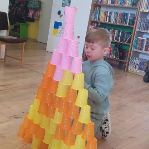 Chłopiec buduje wieżę z kubeczków