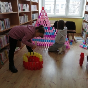 Dwie dziewczynki budujące swoje wieże z kubeczków