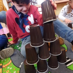 Chłopiec buduje wieżę z kubeczków