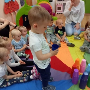 Dzieci wybierają kolory kubeczków w zależności od koloru chusty na której siedzieli