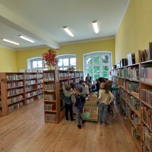 Uczniowie przeglądający książki na półkach