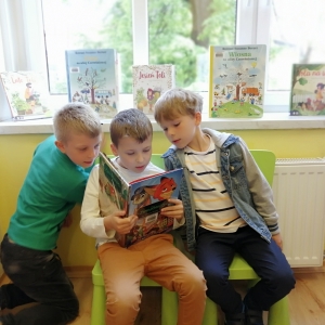 Trzej chłopcy czytający książkę "Zwierzogród"