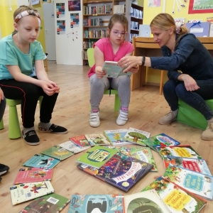 Wolontariuszka pomaga dziewczynce w czytaniu tekstu